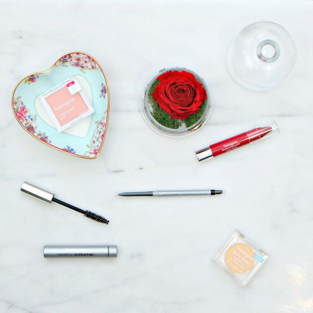 A beautiful Royal Albert dish, a rose in a glass container, and Neutrogena makeup. Lip gloss, mascara, eyeliner, lip tint, and blush.