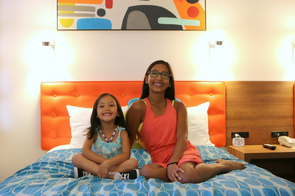 The girls sit on one of the beds inside the family suite at Cabana Bay Beach Resort. 