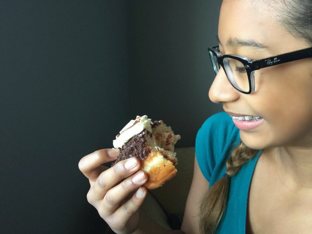 Life gets real, and that means donuts for breakfast, Gabby holds one in her hand and smiles. 