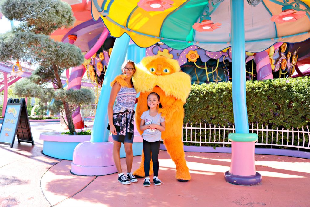 Two girls pose with the Lorax and smile. 