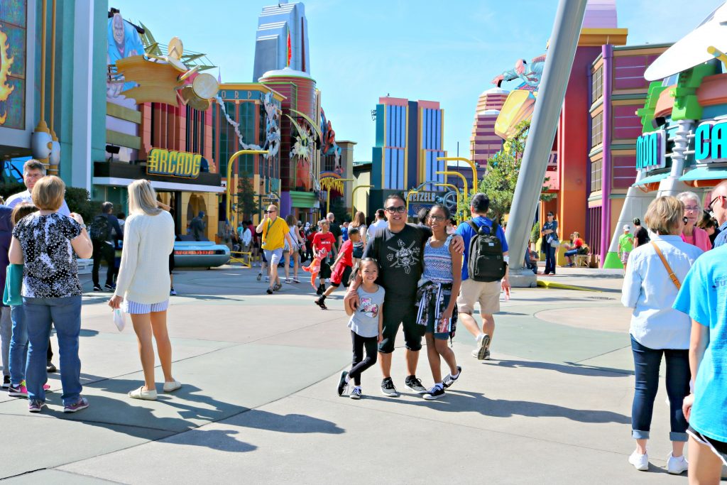 Dad and his two girls stand in the middle of Island of Adventures at Universal Studios. 