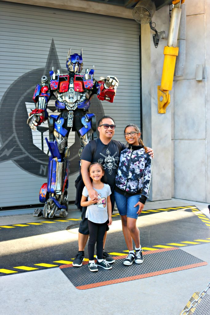 A dad and his two girls pose with Optimus Prime. 