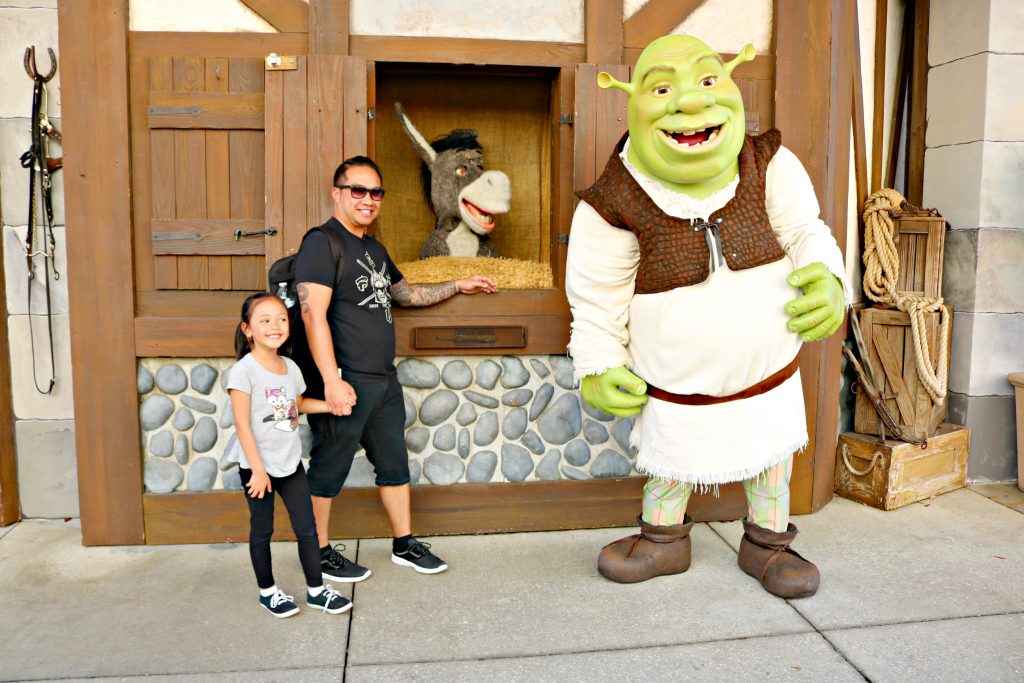 A girl and her dad pose with Shrek and Donkey.