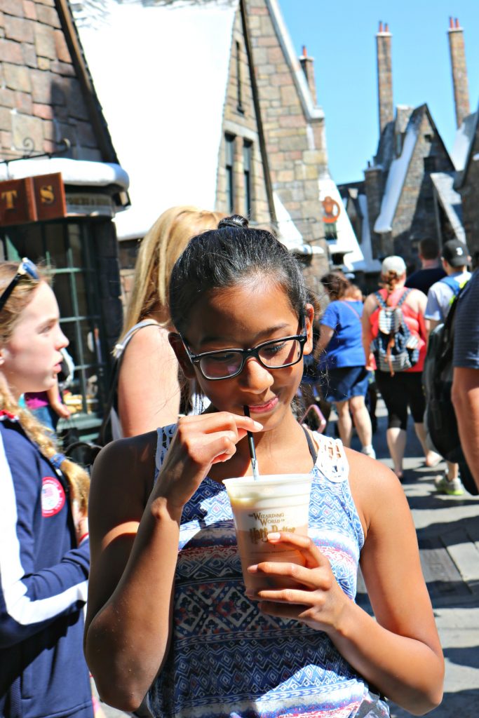 Girl sips on butterbeer in Hogsmeade.