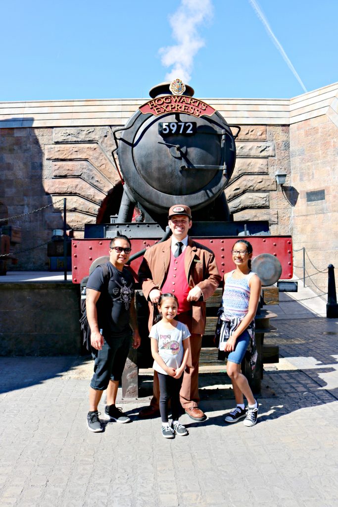 Father and his two daughters pose with the Hogwarts Express conductor.