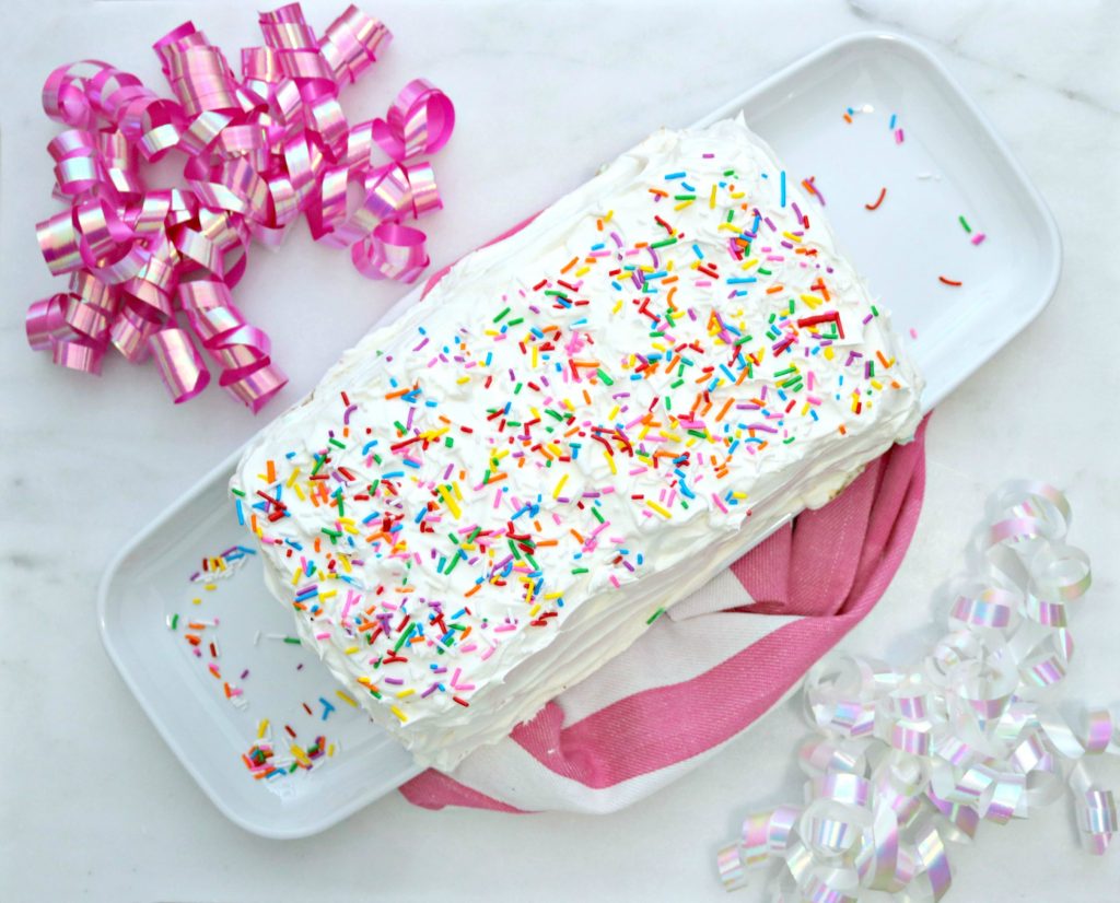 Top view of easy ice cream cake with sprinkles. It is surrounded by pink and white ribbons. 