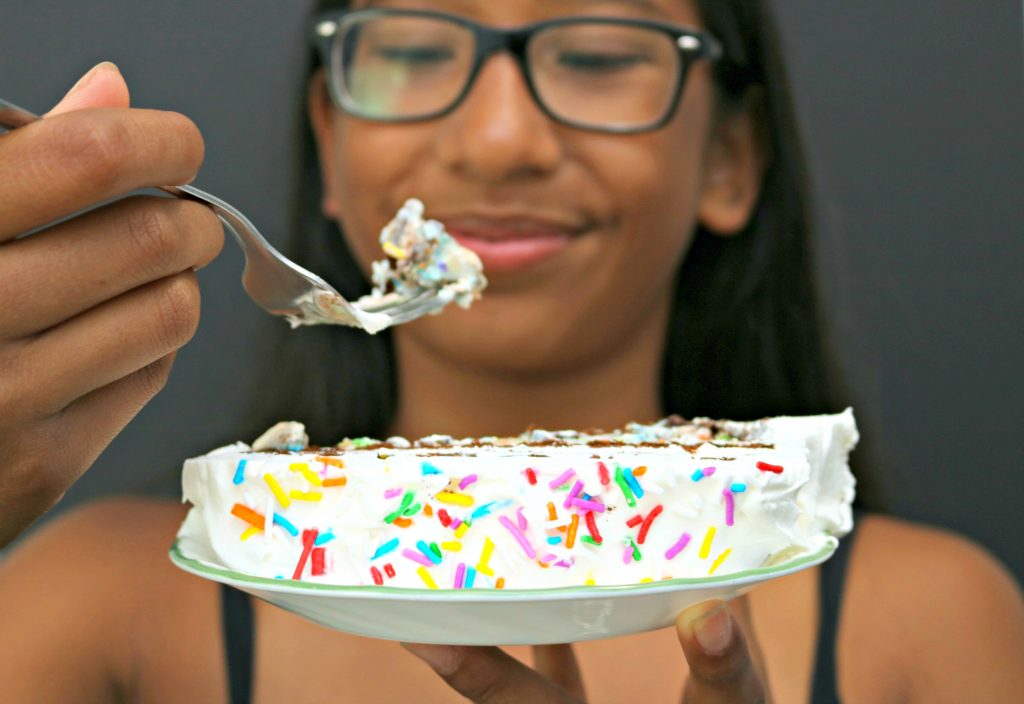 Gabby, a teenager, is shown taking a bite of the cake with a slice in focus. 