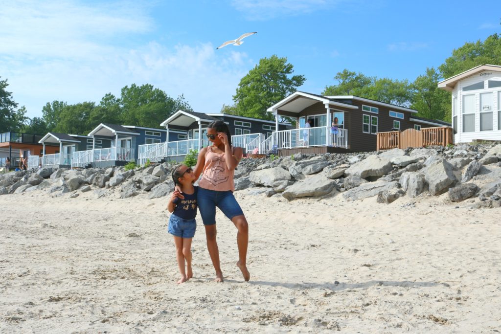 Two girls are looking at each other and smiling at the beach. This article covers why you need to visit Sherkston Shores with your family.