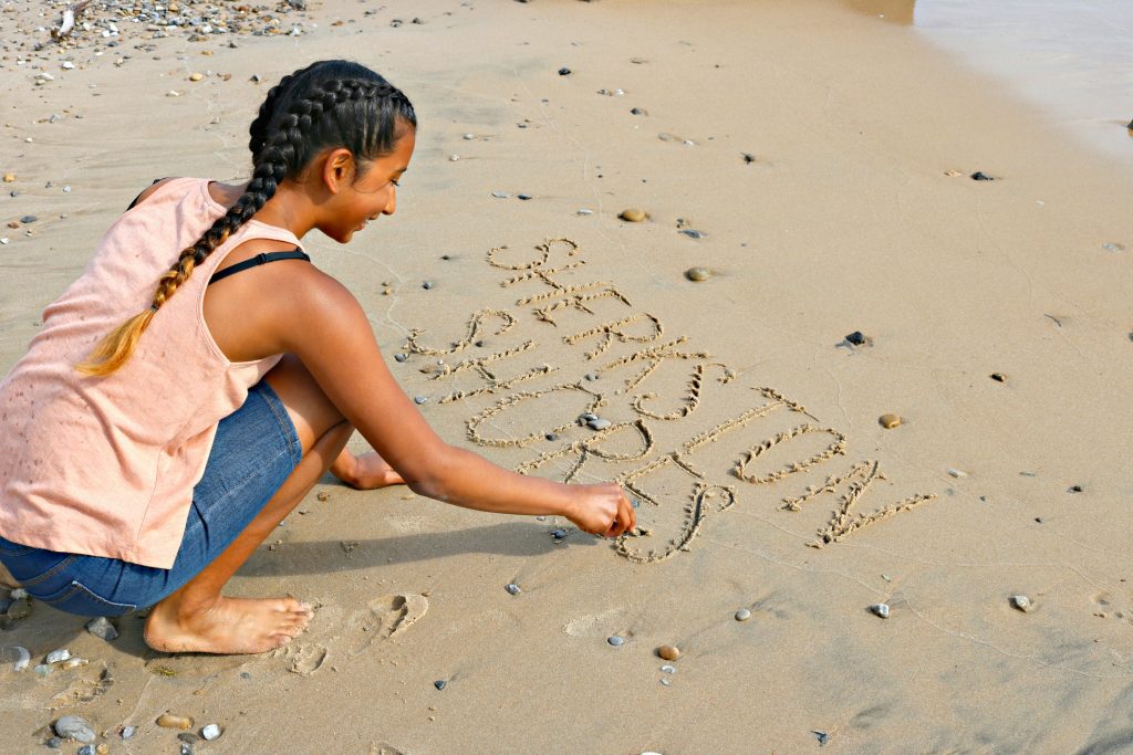 Gabby writes Sherkston Shores on the sand at the beach.