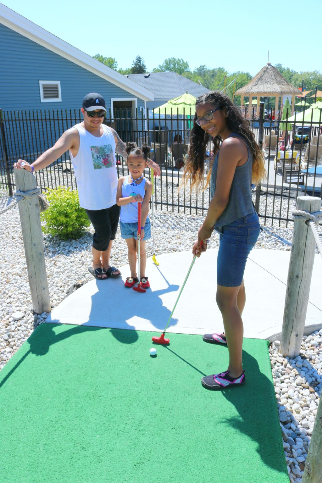 Mimi, Gabby, and Darasak smile and play mini golf. 