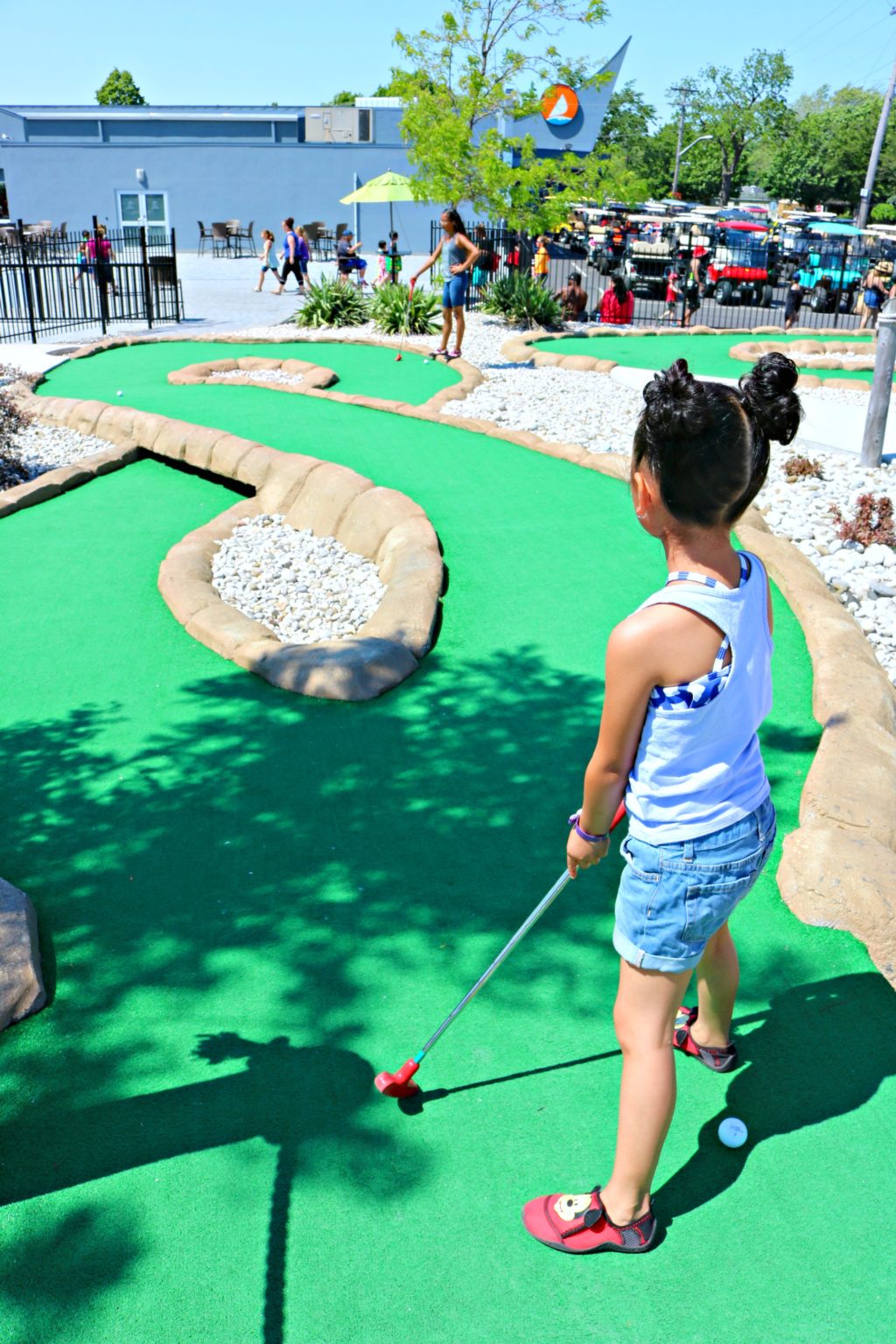 Mimi watchers her ball go down the mini golf lane.