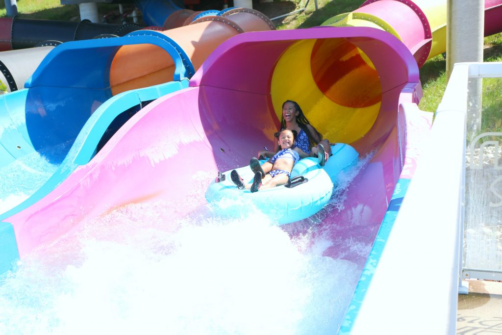 Mimi and Gabby come down the slide in a floatie.