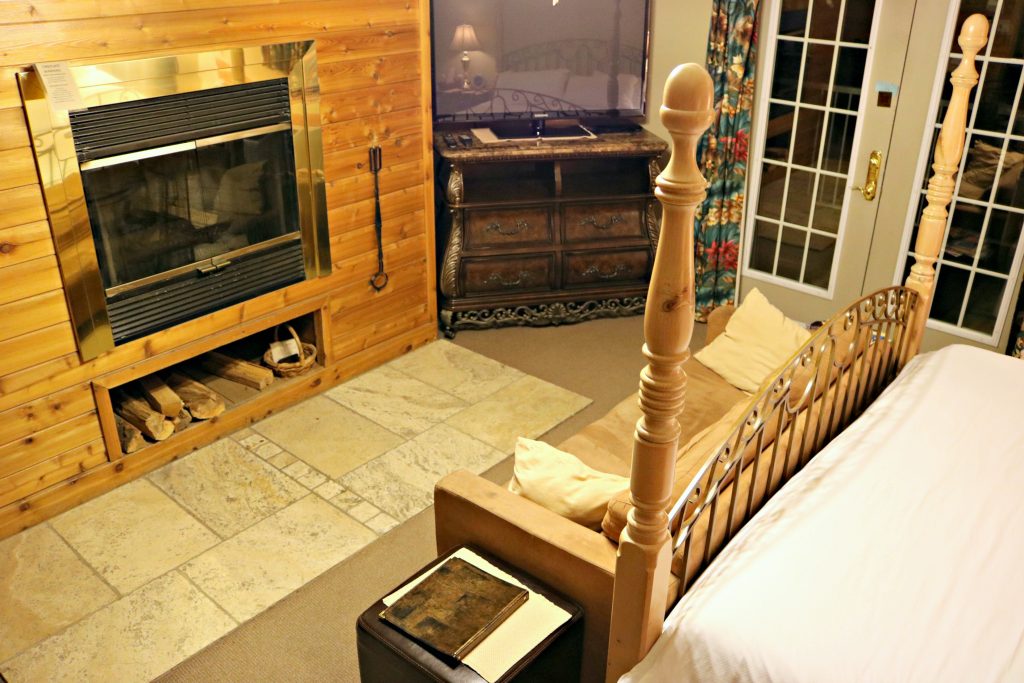 The same bed is pictured and a wood burning fireplace is shown next to a tv stand. 