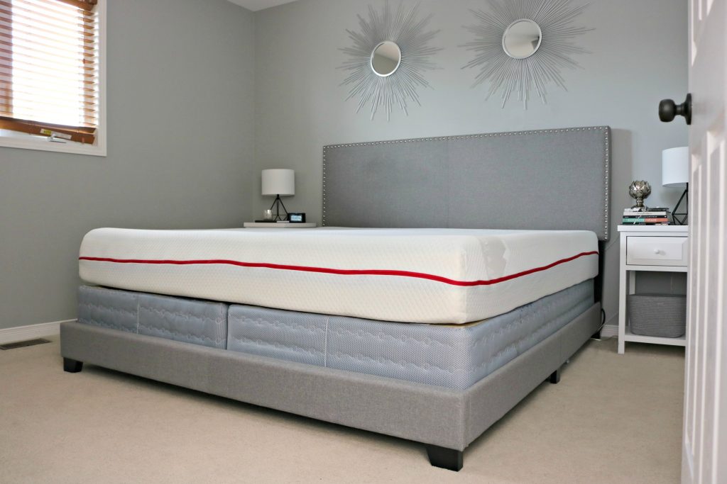 A bed is shown without sheets and showcases the Douglas Foam Mattress by GoodMorning.com.