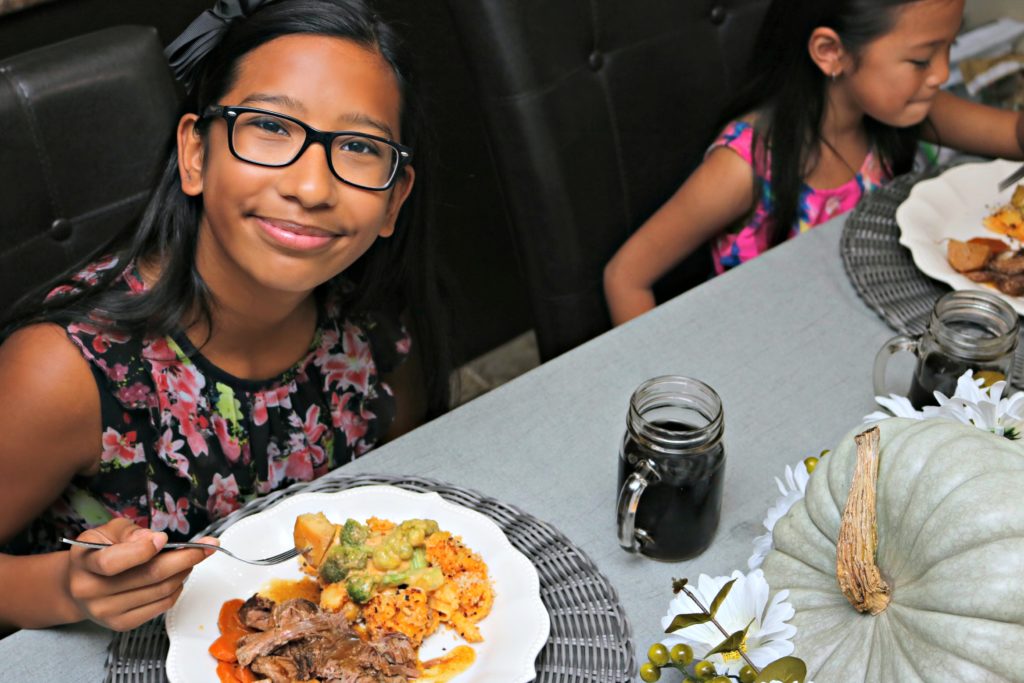 Gabby smiles at camera while eating her meal.