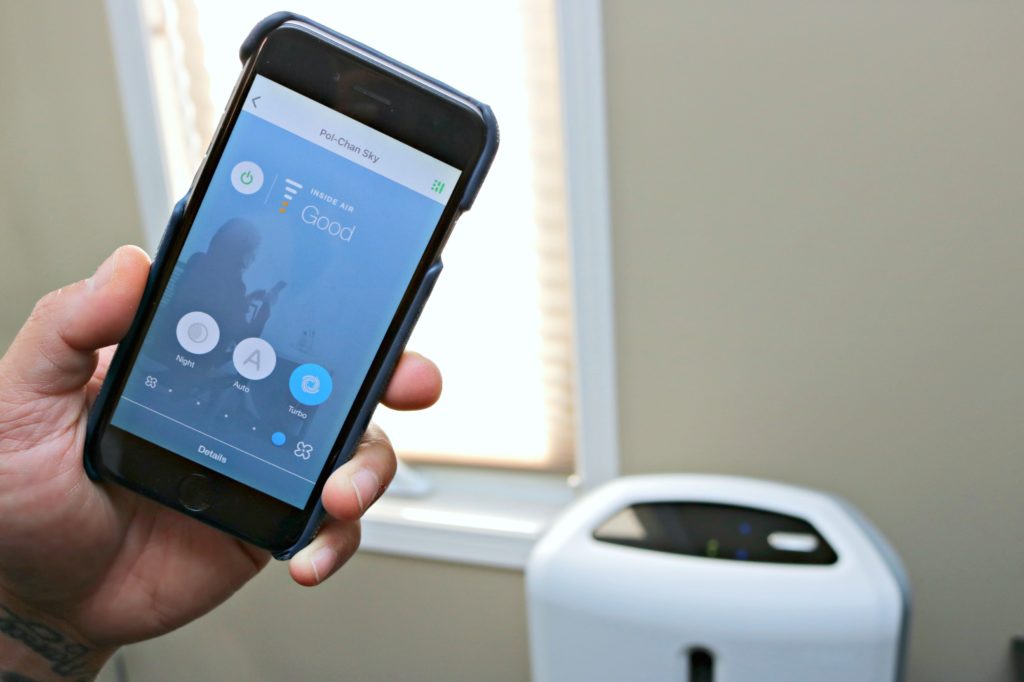 A man holds his cellphone up showing his Atmosphere SKY app showing his air quality is good. 