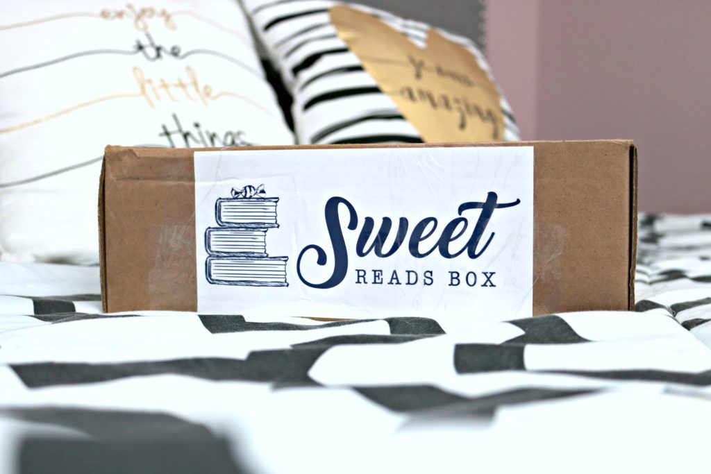 A Sweet Reads Box sits on top of a bed, waiting to be opened. Enjoy Me Time with a Sweet Reads Box Every Month.