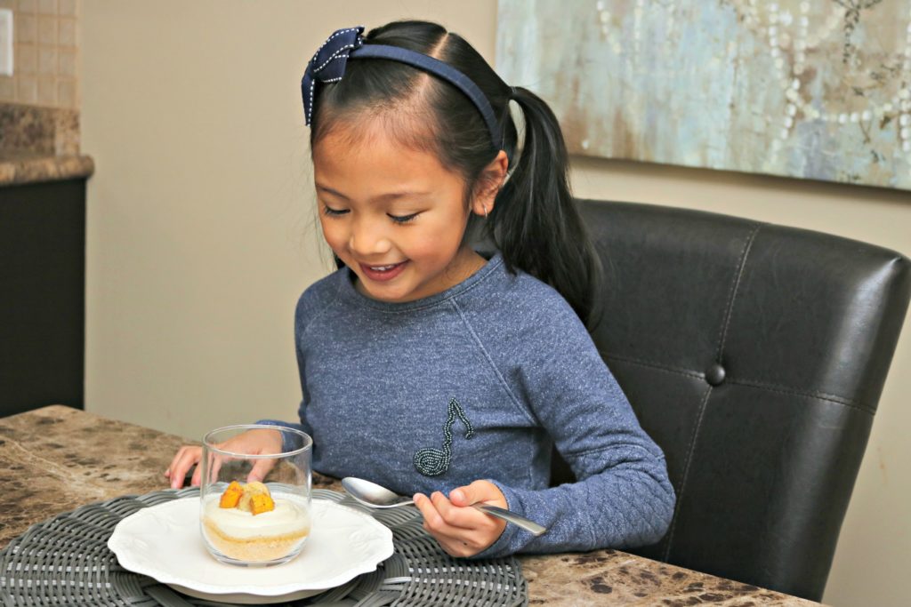 Mimi smiles while she spoons the Mango Cheesecake dessert.