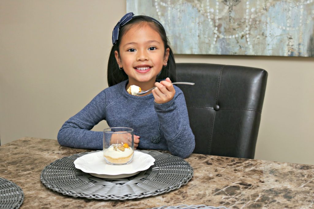 Mimi sits at the table with her mango cheesecake cup.