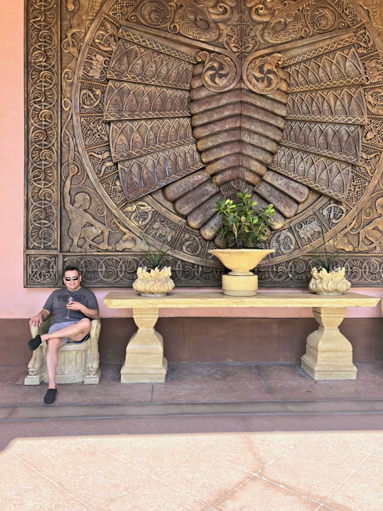 A gentleman sits in front of a huge art piece in Atlantis Resort and enjoys a glass a wine.