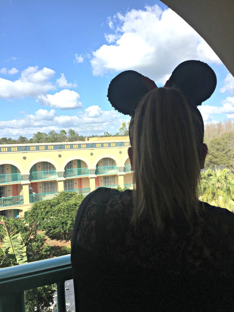 A woman looks out the Coronado Springs resort with her Minnie Ears.