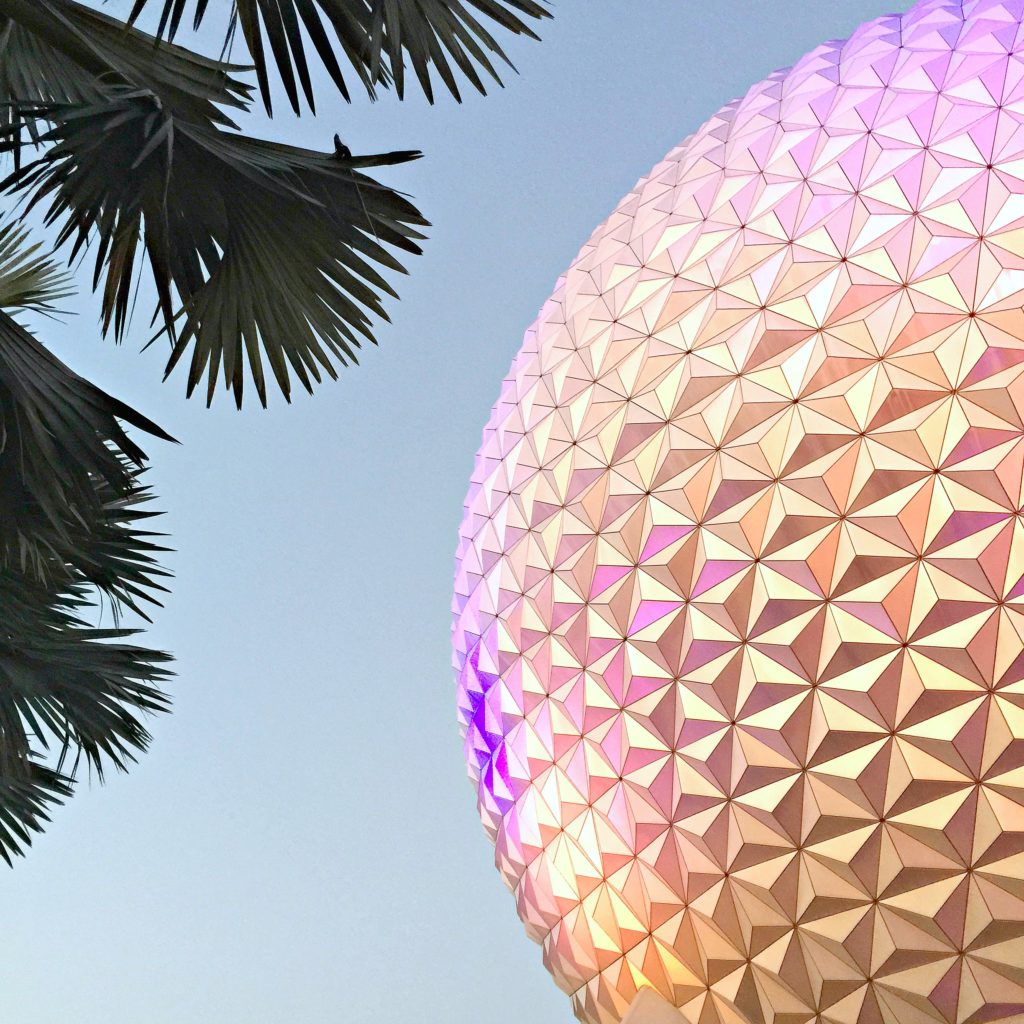 The Epcot Ball half in view with palm trees.