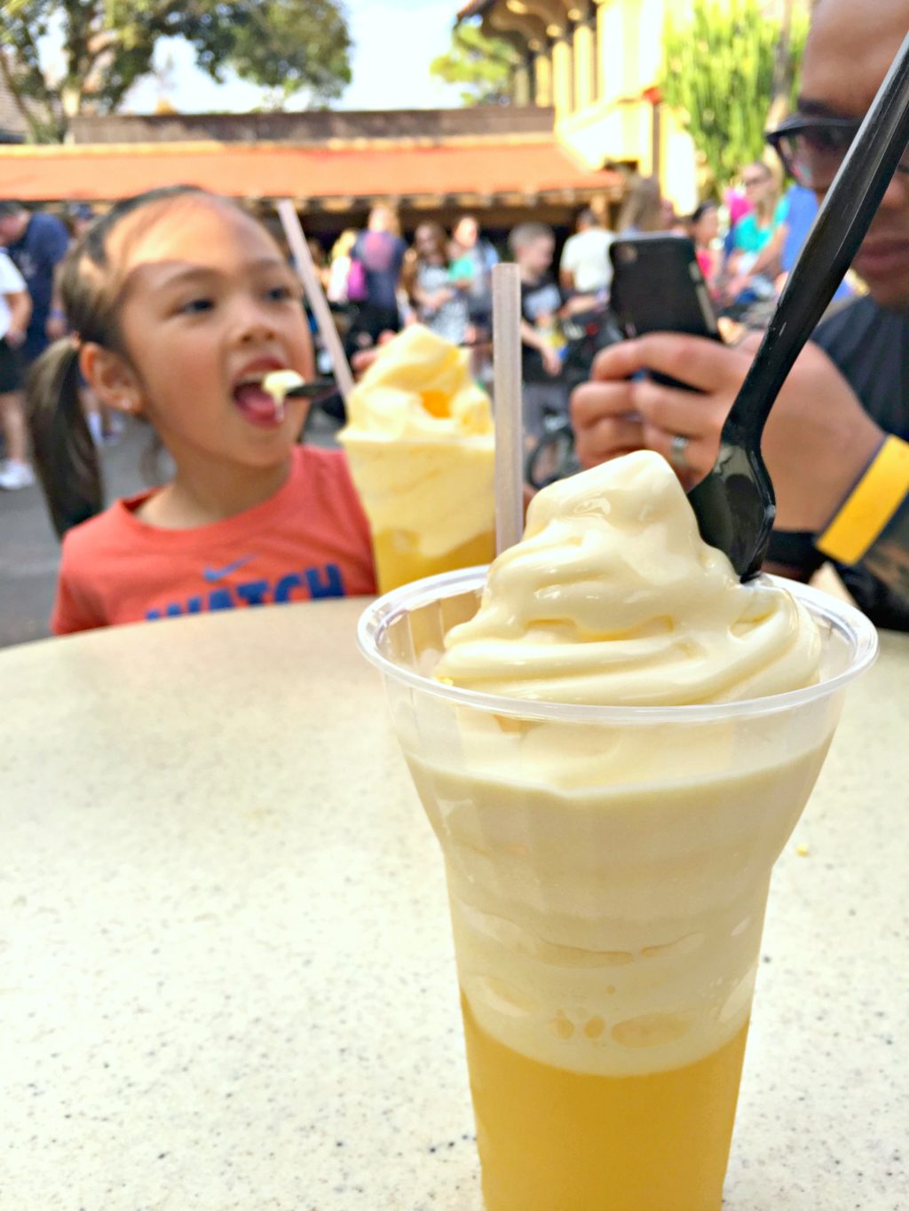 A Dole Whip is pictured while a child enjoys a Dole Whip in the background.