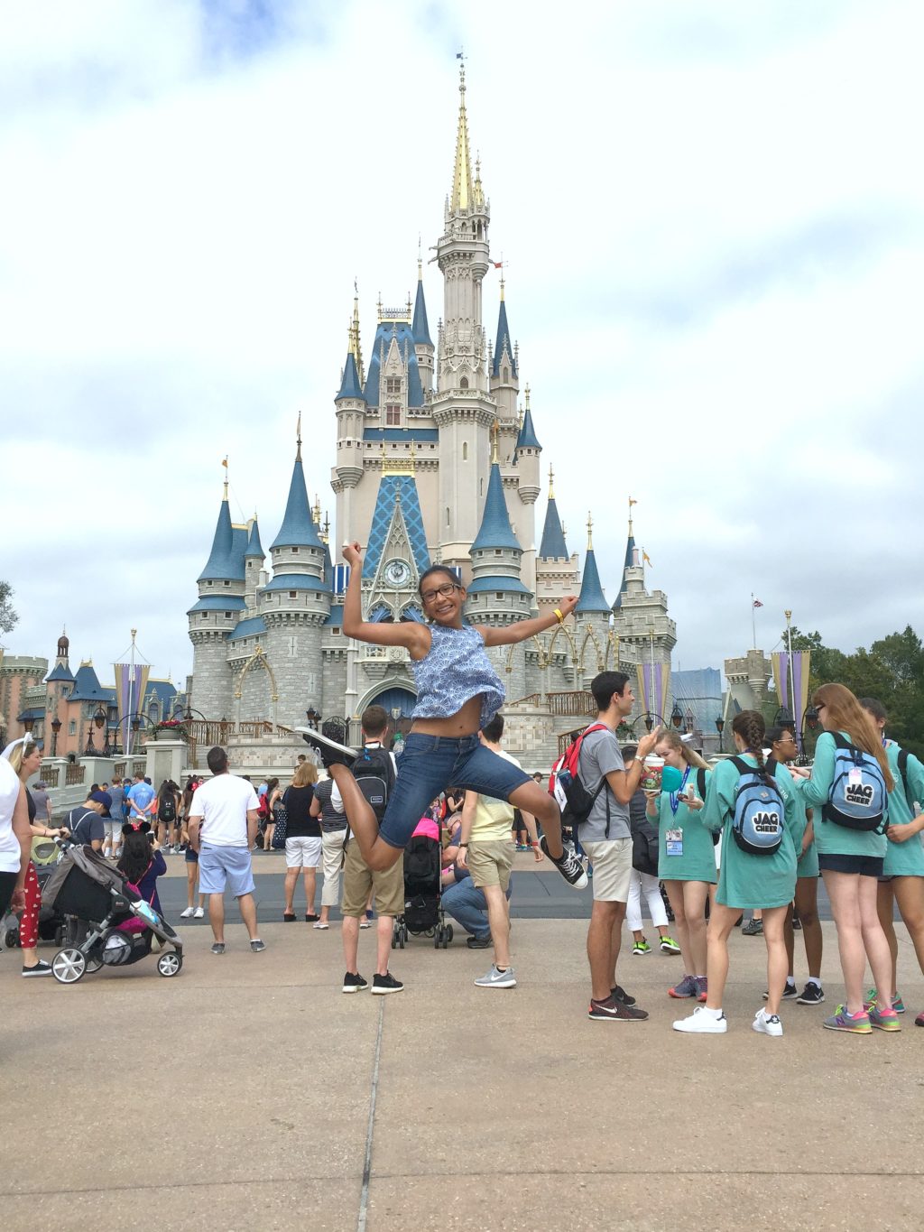 A girl jumps in front of Cinderella's castle in Magic Kingdom. 