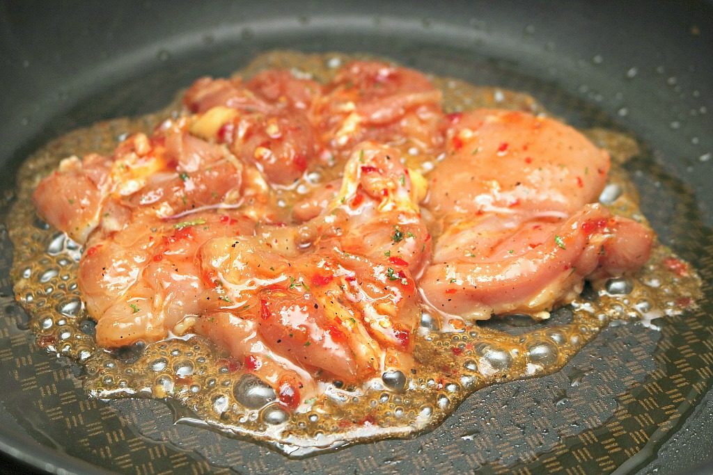 Marinated chicken is being seared in pan.