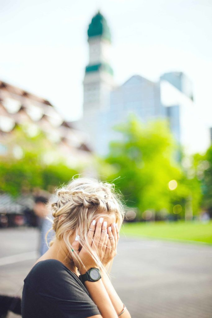 Woman looks stressed and holds head in hands.