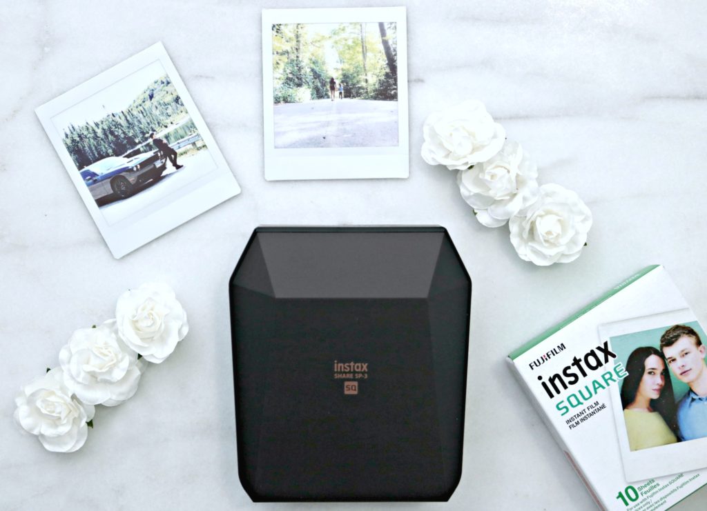 Instax printer with printed out square pictures and flowers. 