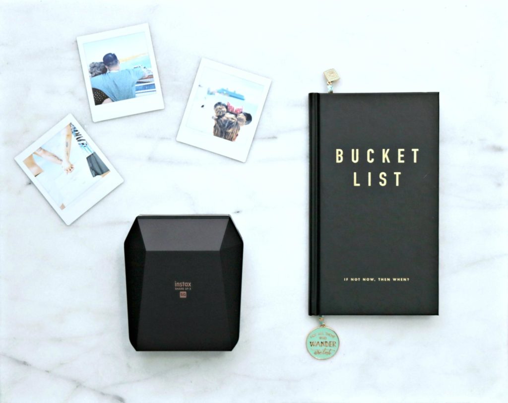 A bucket list journal, Instax printer and pictures are shown. 