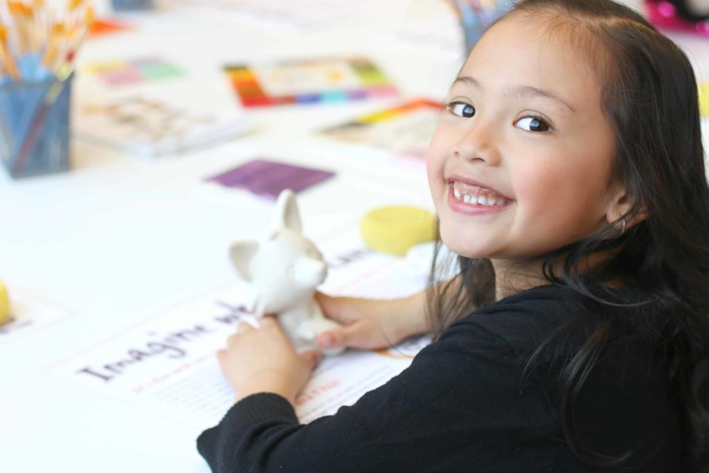 A little girl waits for paint to paint her fox pottery piece at Crock A Doodle. 