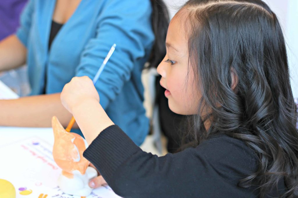 A little girl paints a fox. 