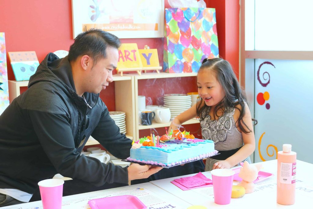 A little girl excitedly blows out her candles on her cake at Crock A Doodle. 