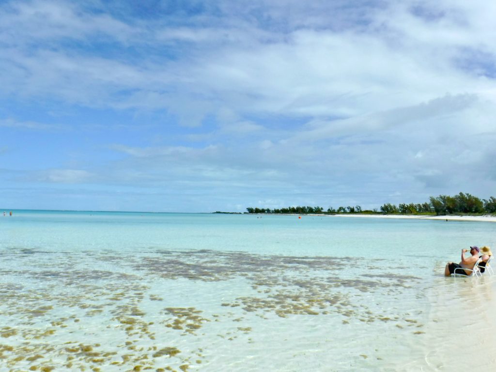 A couple sit in the beautiful Serenity Bay beach. 