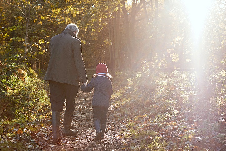 Grandfather And Granddaughter Enjoying Autumn Walk