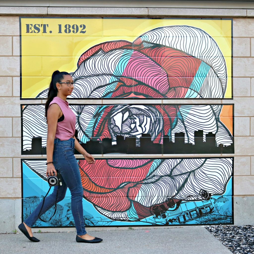 A girl moving on to her next conquest of art, walking with an Instax Square SQ6 in her hand.