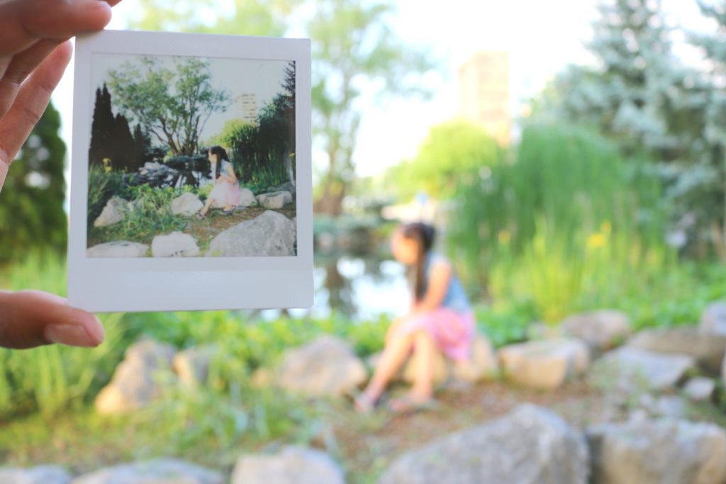 An Instax print is held in front of the camera while the subject is blurred in the background. 