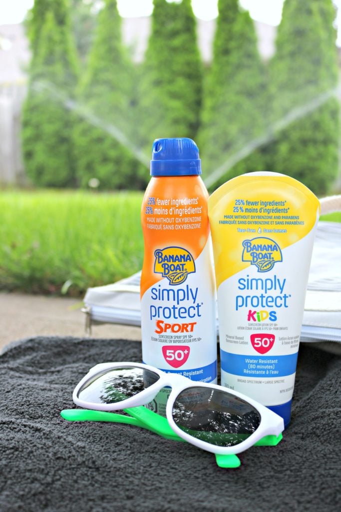 A beach bag, sunglasses and two Banana Boat sunscreens are shown with a sprinkler in the background. 