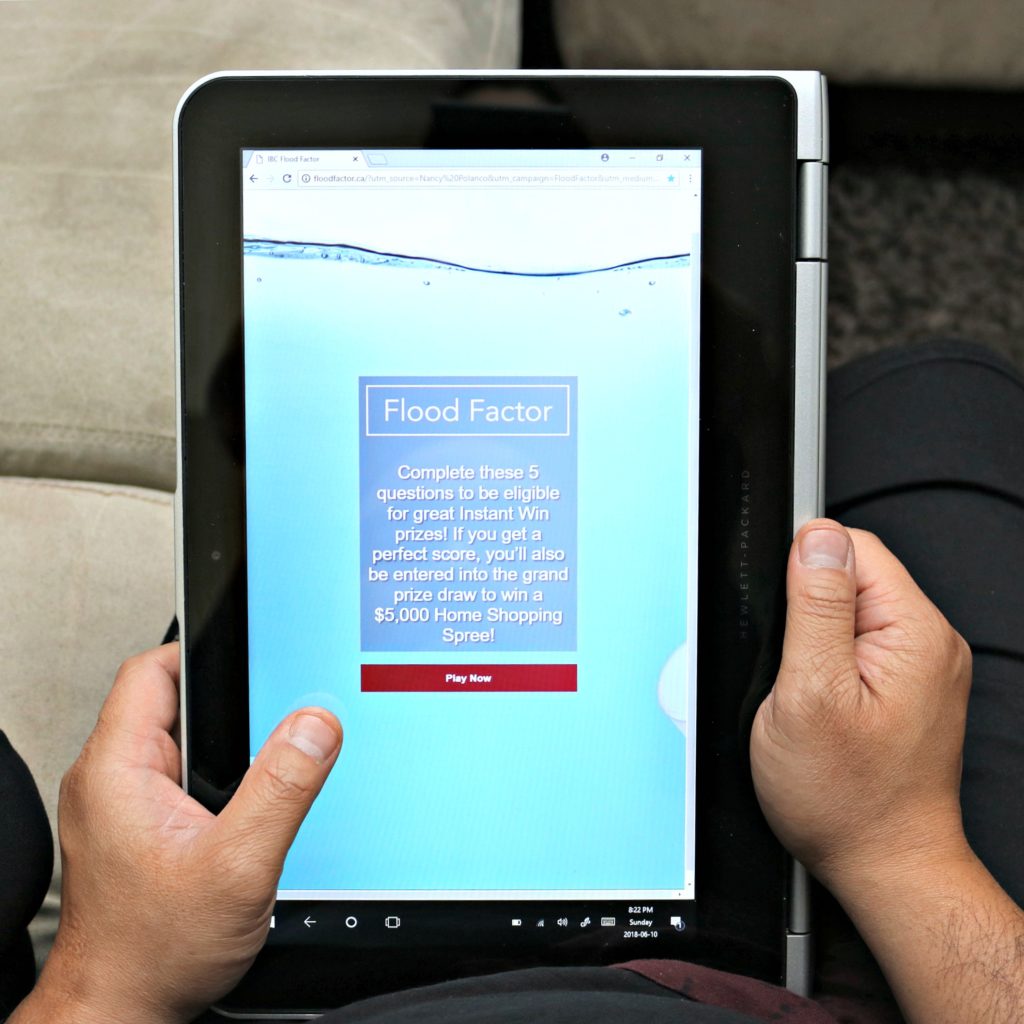 A man holds a tablet showing the Flood Factor Quiz.