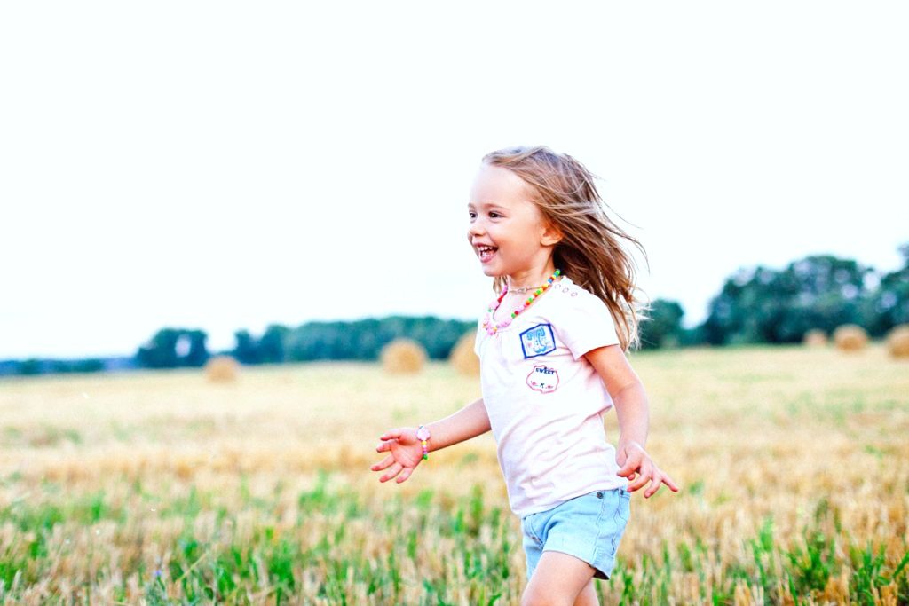 Little girl smiles and runs in a field. 