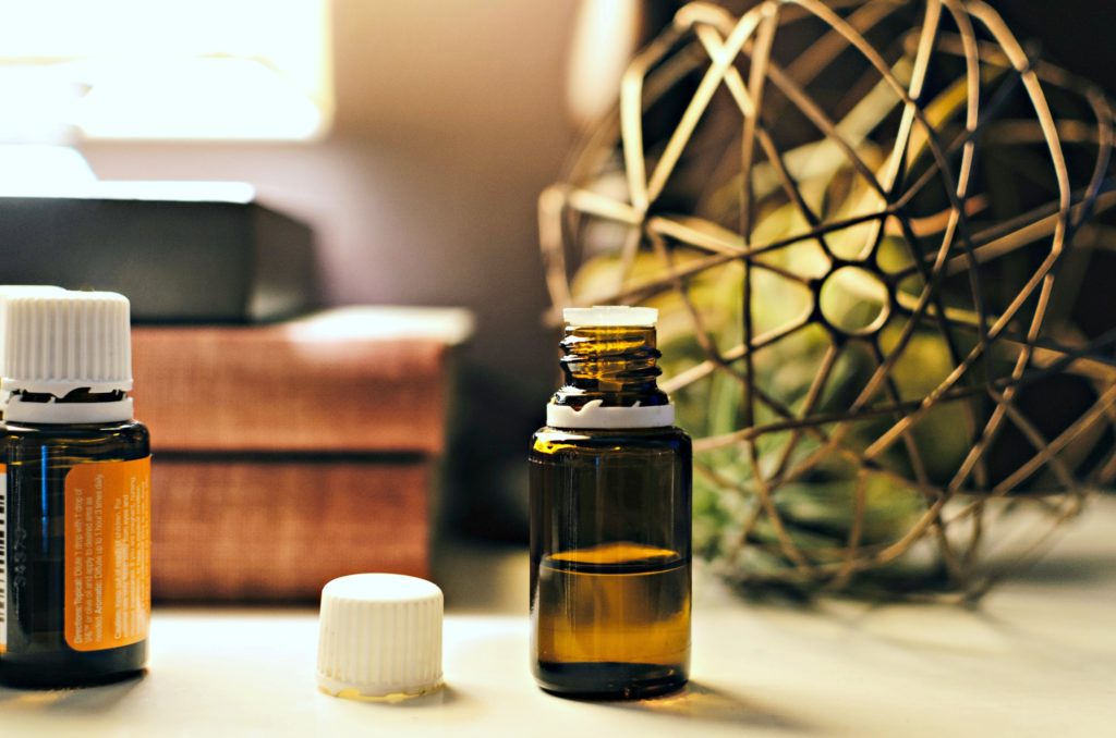 A vial of essential oils sits on a dresser. 