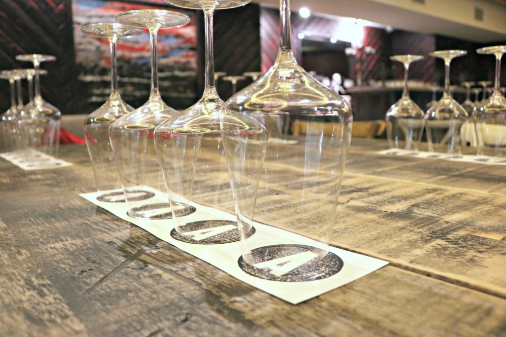 Wine glasses are lined up, ready to help customers sample Adamo wine. 