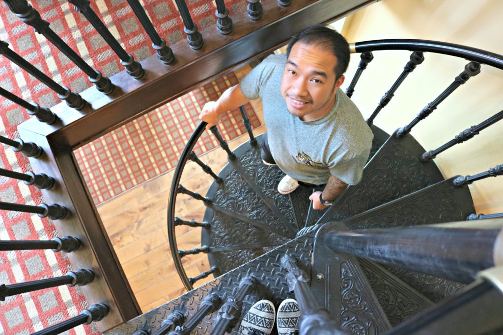 A man looks up at his wife while going down a spiral staircase. The wife's feet are pictured.