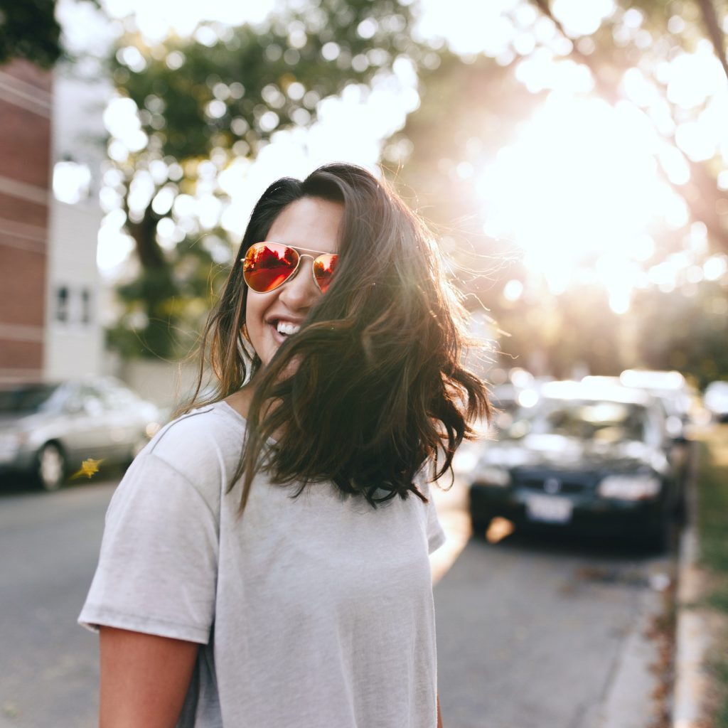 A woman smiles as the sun sets behind her. 