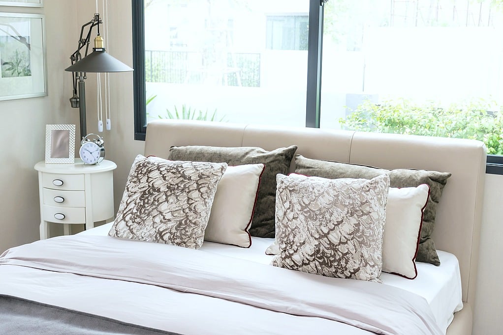 modern bedroom design with bed, pillows and lamp on table