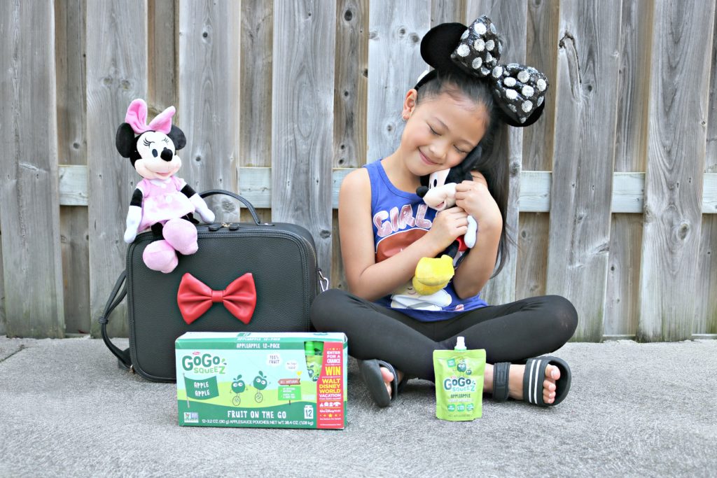 A little girl hugs Mickey Mouse and hopes to win a trip to Disney World with GoGo SqueeZ!