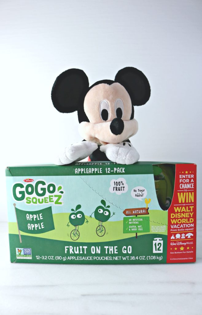 Mickey stands behind a GoGo SqueeZ box with instructions on how to win a trip to Disney World. 