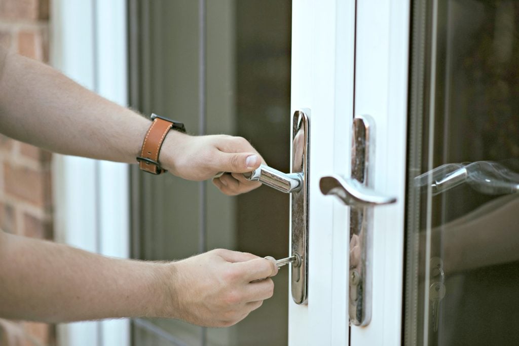 A man puts key into keyhole and opens door to new home.